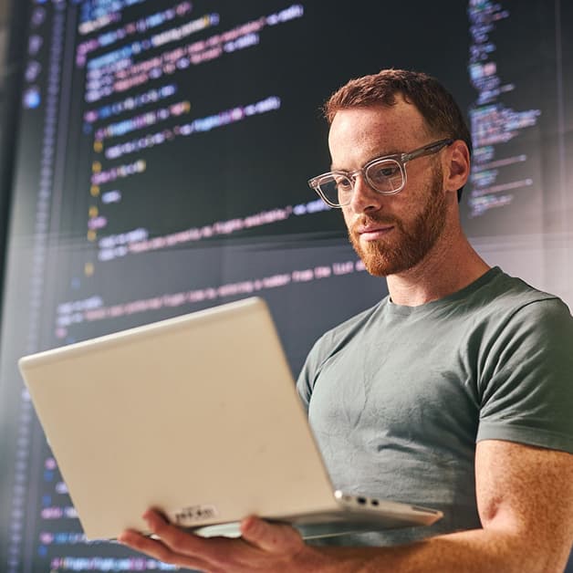 Software developer working on a laptop in front of programming code