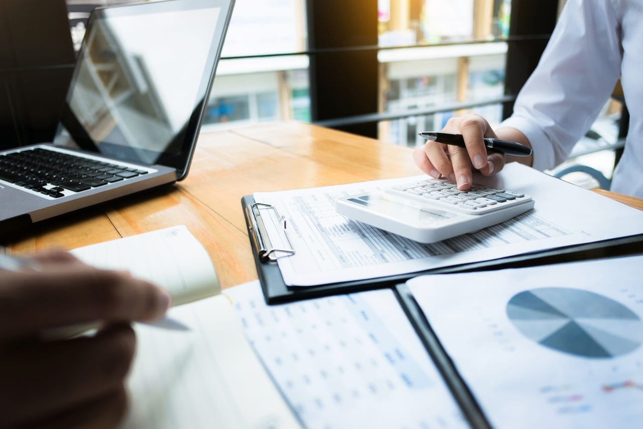 Professional using a calculator while reviewing financial reports
