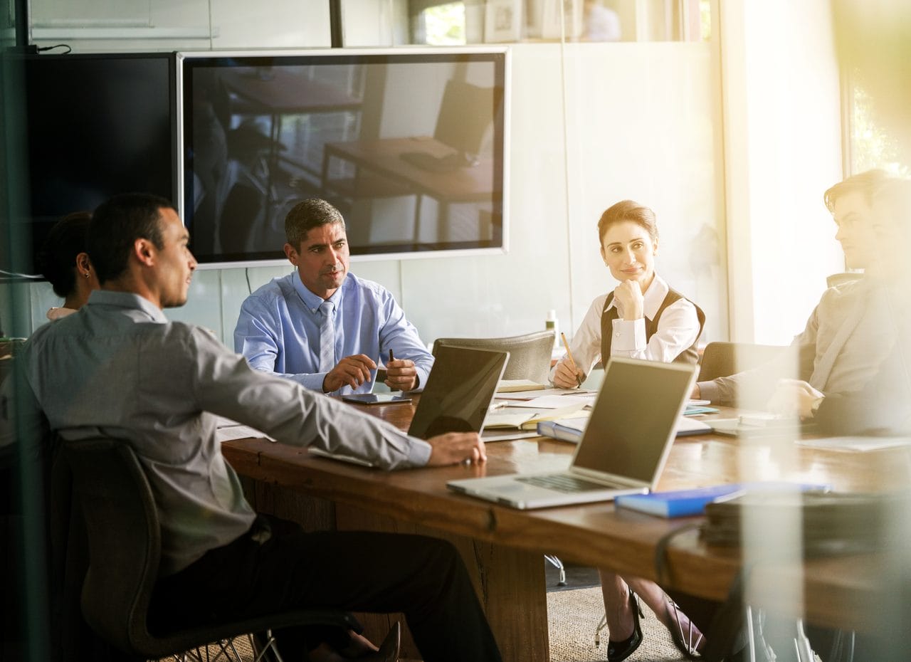 Business team discussing work around laptops in a meeting room
